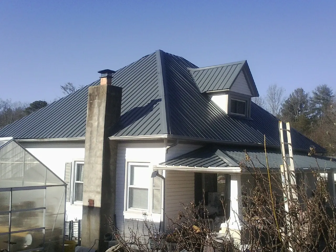 Dark blue standing seam metal roof on a white farmhouse with dormer — Slate & Tile Roof Repair by Roofing Brothers in Hathorne