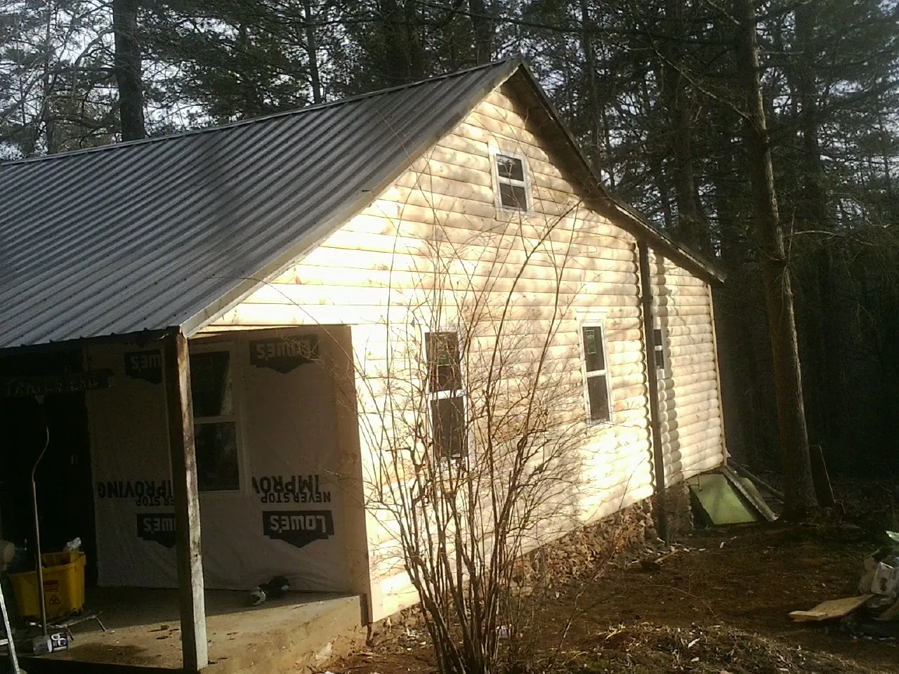 Log siding gable end under a dark metal roof edge in Hathorne