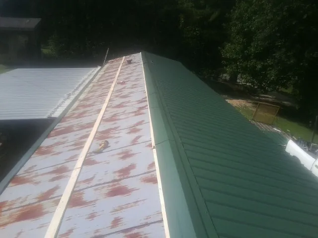 Old rusted panels beside newly installed green metal roofing — Wind Damage Roof Repair by Roofing Brothers in Hathorne