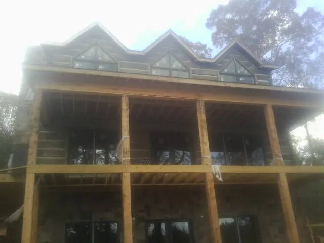 Dormers and porch framing on a large log home under construction — Roof Coating work by our crew in Hathorne