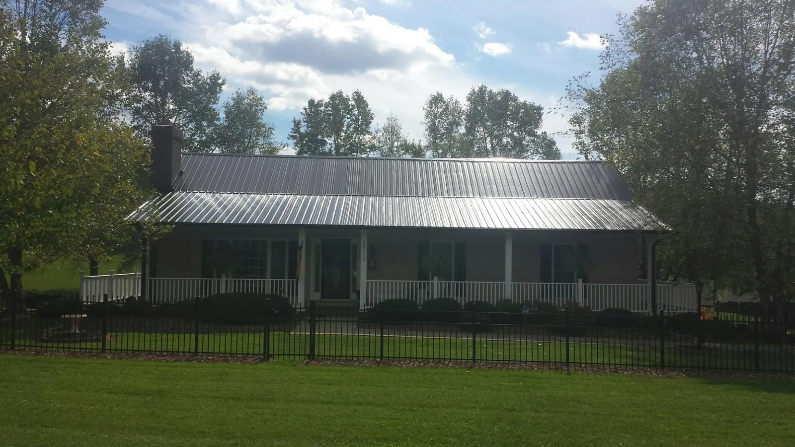 Gray metal roof on a brick ranch with a full width front porch — Gutter Guard Installation work by our crew in Hathorne