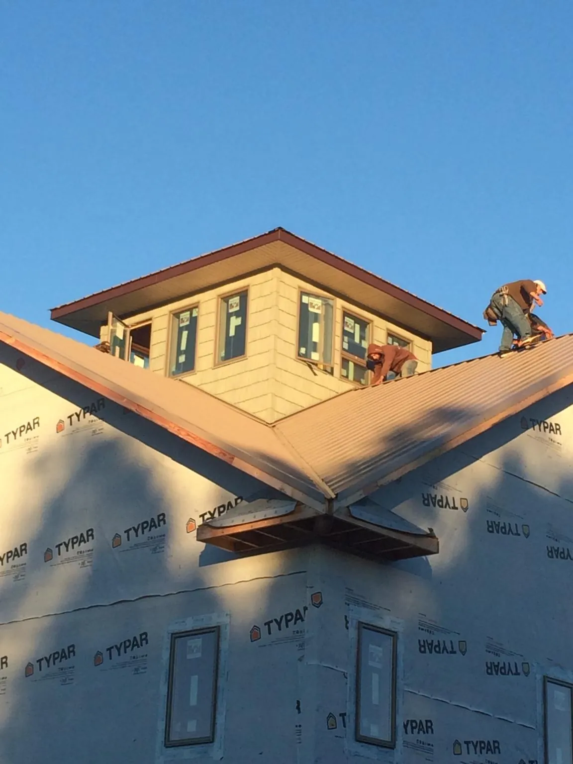 Roofers working around a rooftop cupola on a new metal roof at sunset — Roof Waterproofing in Hathorne by Roofing Brothers